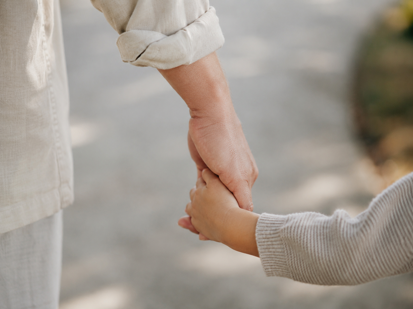 Close-up of an adult holding a child’s hand.